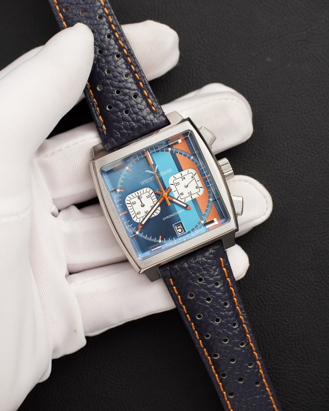 Specht & Söhne SP0009 VK chronograph held in a gloved hand, showing the two pushers, 60-unit counter and 24-hour sub-dial