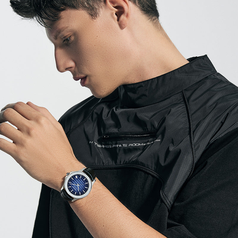 Agelocer Baikal Big Date automatic watch with a ribbed blue dial worn on the wrist of a man in a black technical jacket