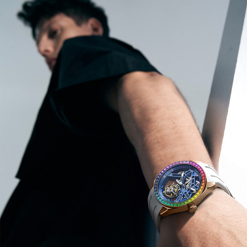Agelocer Tourbillon Rainbow Bezel Ceramic in White Blue Rose Gold on the wrist, rose gold case and white rubber strap with a graduated rainbow zirconia ceramic bezel over a blue skeleton dial