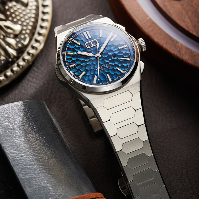 Lucky Harvey ZLS402-1 sonnerie au passage watch with ocean blue hammered dial and steel bracelet styled beside a brass medallion and leather