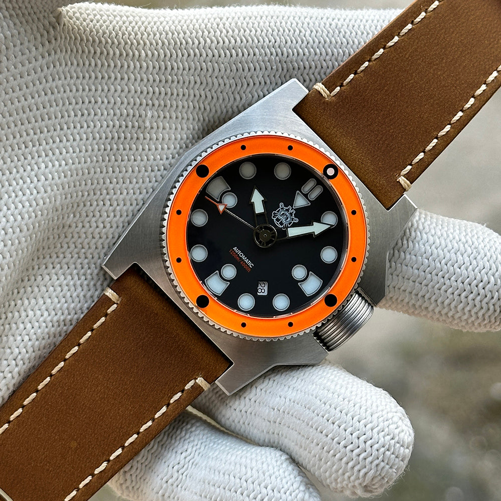 STEELDIVE SD2213 black dial and orange bezel held in a gloved hand on brown leather