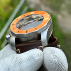 Angled view of the STEELDIVE SD2211 orange bezel and sapphire crystal on brown leather