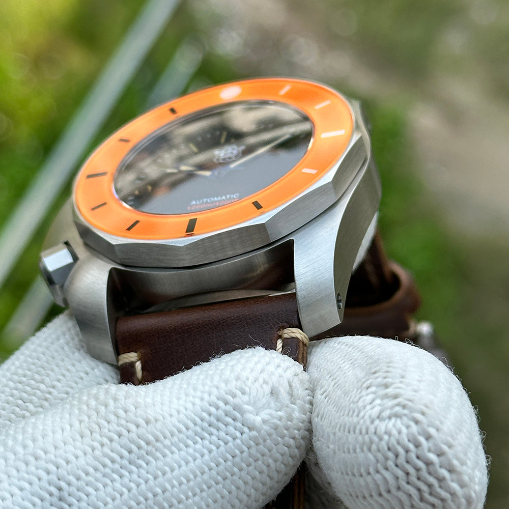 Angled view of the STEELDIVE SD2211 orange bezel and sapphire crystal on brown leather