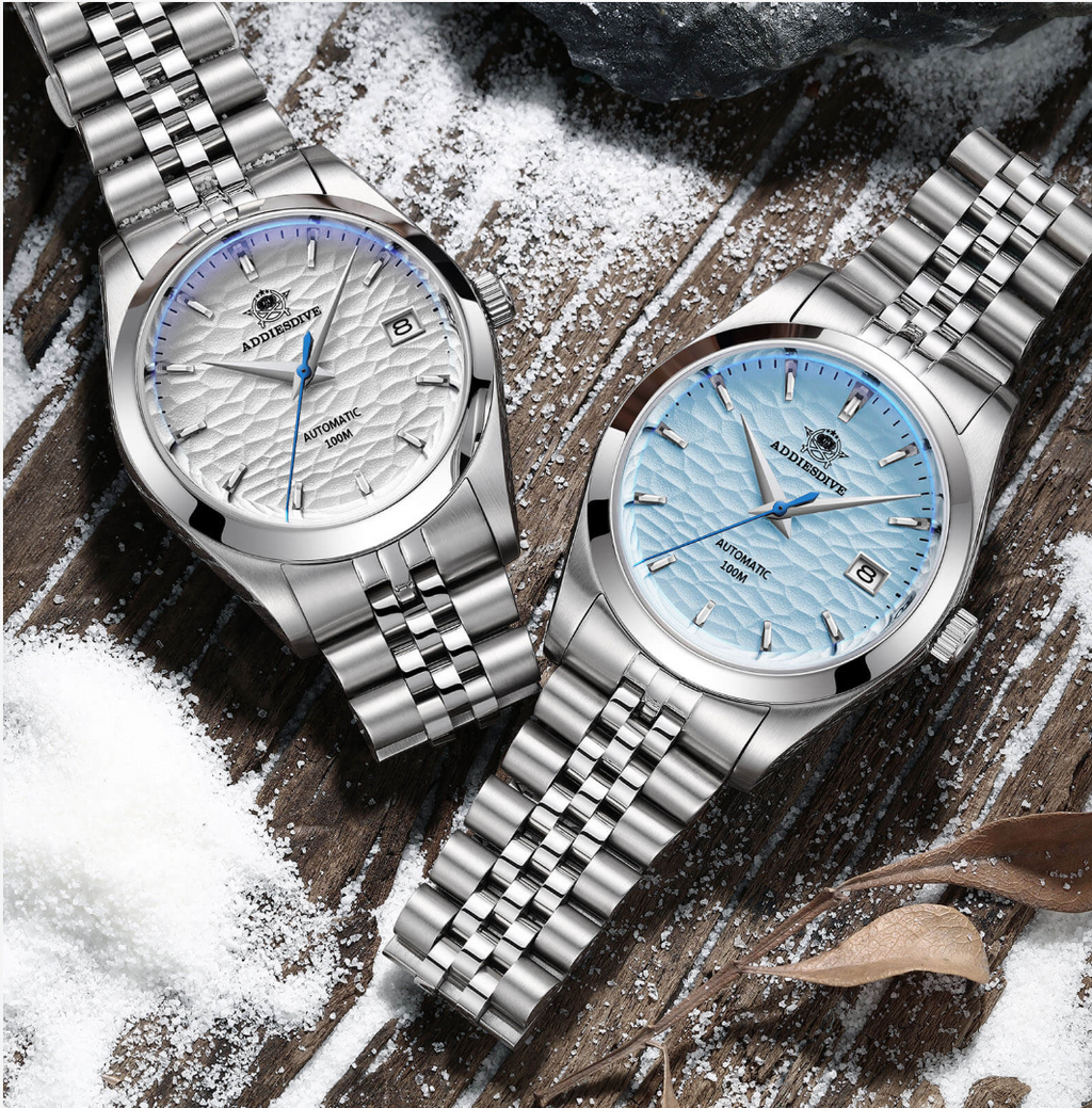 Two silver watches with blue faces on a textured surface