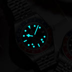 ADDIESDIVE AD2044 GMT showing bright cyan luminous hands and markers in dark on steel bracelet