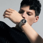 Man checking the Agelocer Budapest big-date automatic watch with black dial on a steel bracelet, wrist view