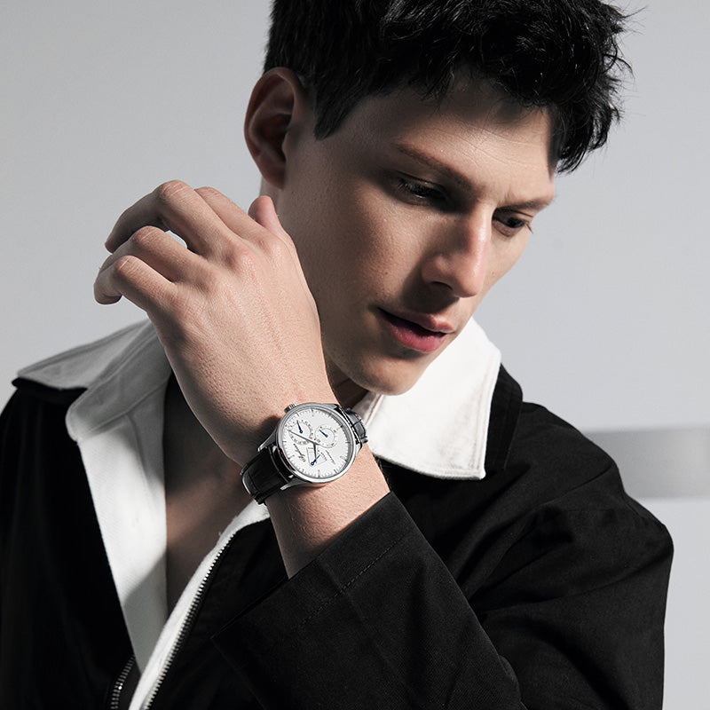 Male model wearing Agelocer Budapest power reserve automatic watch with white dial, studio lifestyle shot
