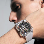 Man wearing Agelocer transparent crystal square tourbillon watch on white rubber strap, wrist view