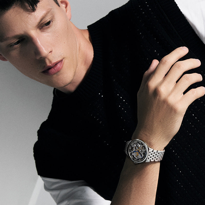 Man wearing Agelocer Schwarzwald double-sided skeleton watch on a steel bracelet, wrist view