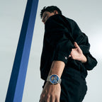 Male model wearing Agelocer Free-Sprung diamond tourbillon watch with steel bracelet, dynamic lifestyle shot