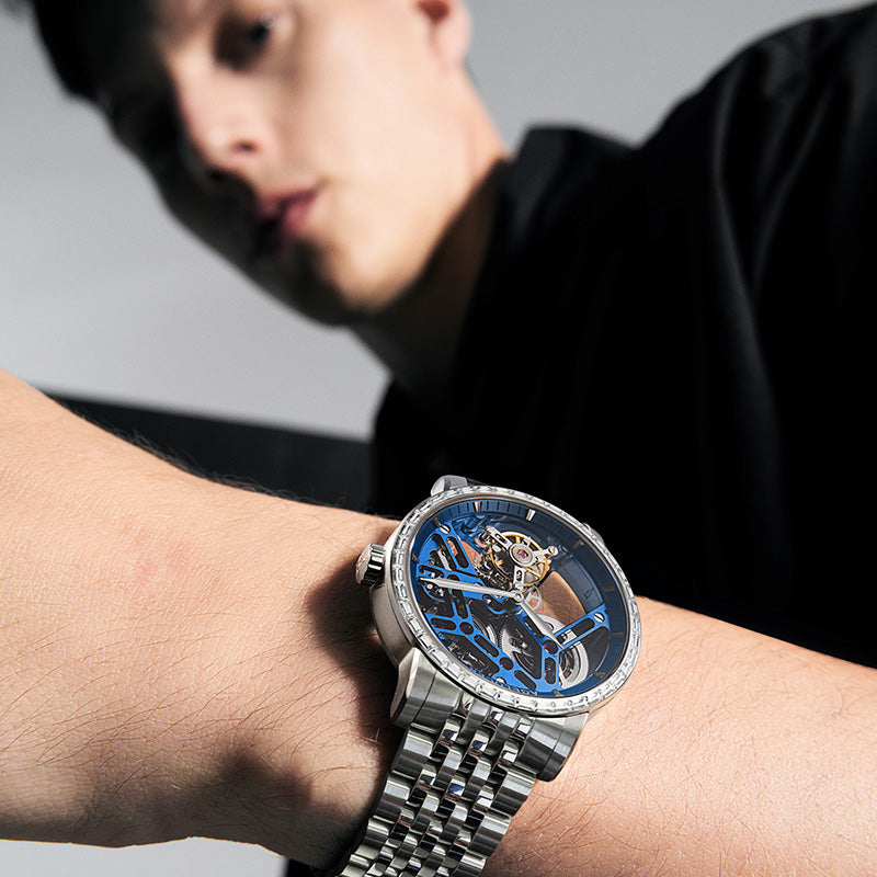 Agelocer Free-Sprung diamond tourbillon watch with blue dial and steel bracelet worn on the wrist, close-up