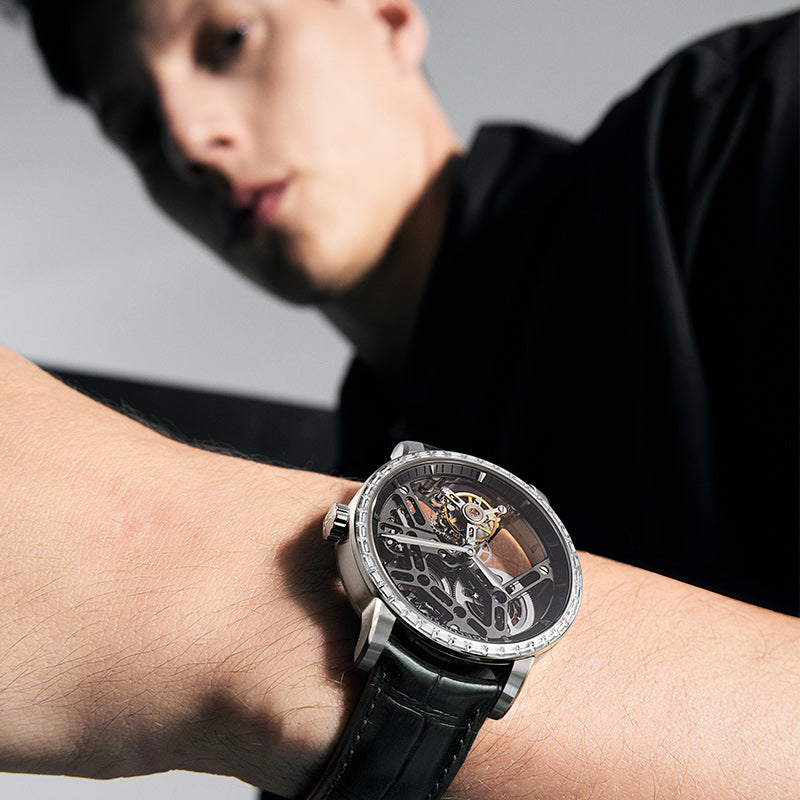 Man wearing Agelocer free-sprung diamond tourbillon watch, steel case and black leather strap, wrist view