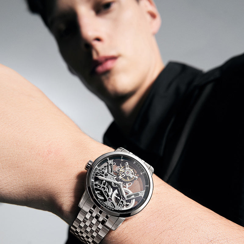 Man wearing Agelocer flying tourbillon skeleton watch on a steel bracelet, wrist view
