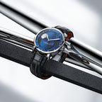 Agelocer Astronomer galaxy moonphase watch with blue starry dial resting on polished steel bars, lifestyle