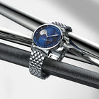 Agelocer Astronomer galaxy moonphase watch with steel bracelet resting on polished steel bars, lifestyle shot