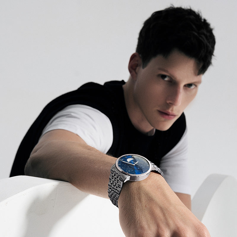 Male model wearing Agelocer Astronomer galaxy moonphase watch on a steel bracelet, studio lifestyle shot