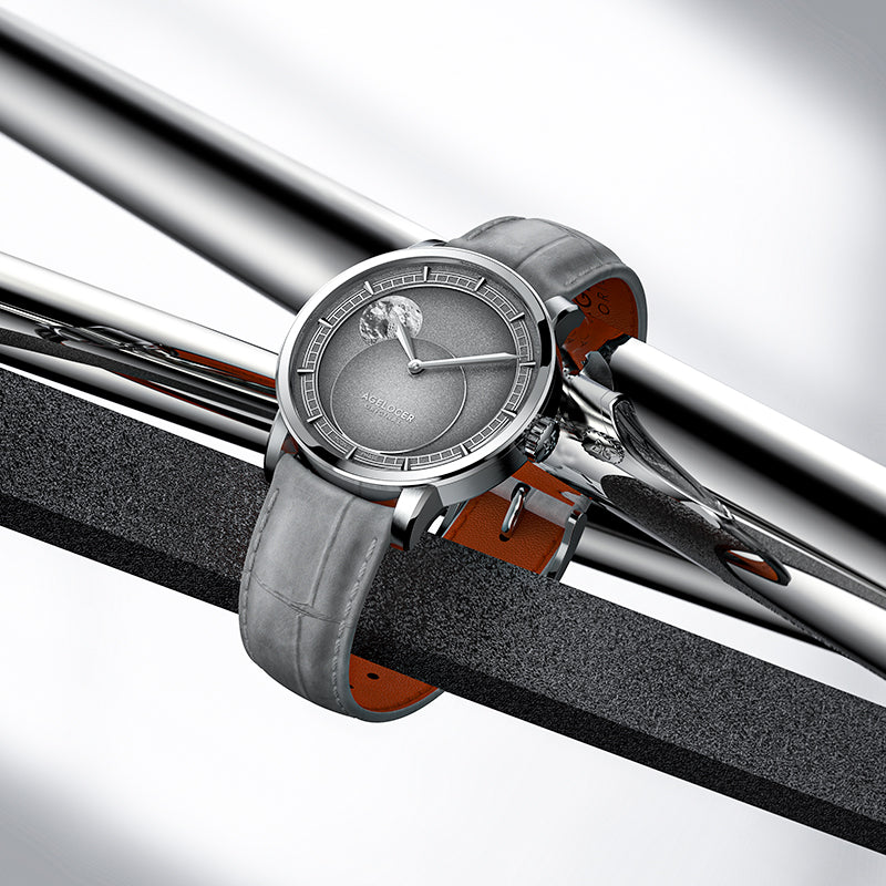 Agelocer Astronomer moonphase watch with steel case and grey strap resting on polished steel bars, lifestyle