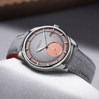 Agelocer Petite Seconde automatic watch with salmon accents on grey fabric, angled lifestyle shot