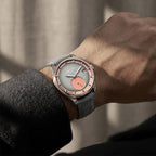 Man wearing Agelocer Petite Seconde automatic watch with salmon dial accents on grey strap, wrist view