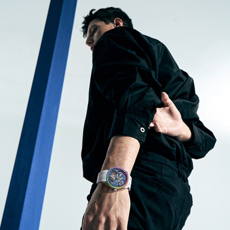Male model wearing Agelocer rainbow bezel tourbillon skeleton watch with white strap, studio lifestyle shot