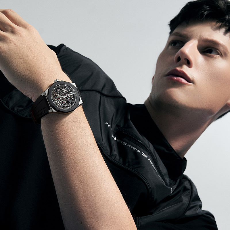 Man wearing Agelocer Schwarzwald silver skeleton automatic watch on black rubber strap, wrist view