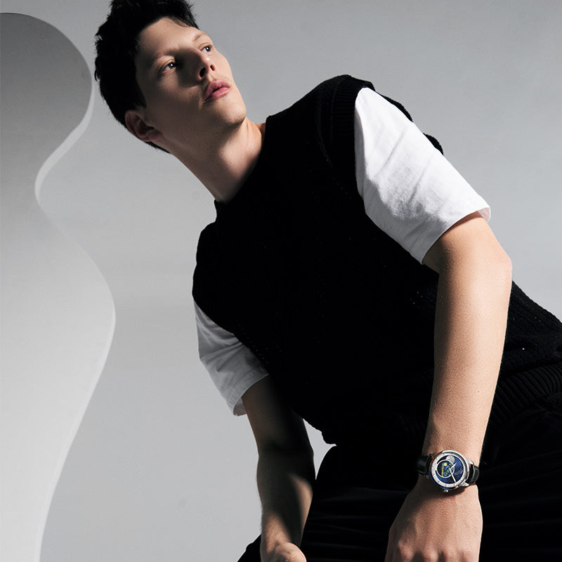 Male model wearing the Agelocer Astronomer painted Starry Night moonphase watch, seated lifestyle shot