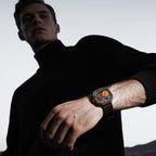 Man wearing Agelocer Volcano orange carbon fibre skeleton watch on black rubber strap, lifestyle portrait