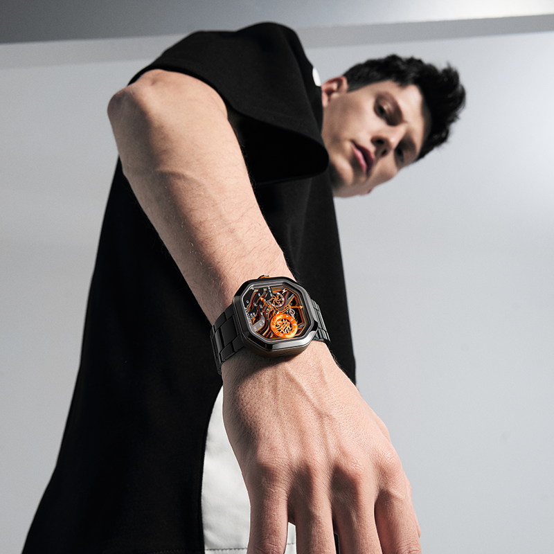 Male model wearing Agelocer Volcano Flame steel-bracelet watch with orange dial, studio lifestyle shot
