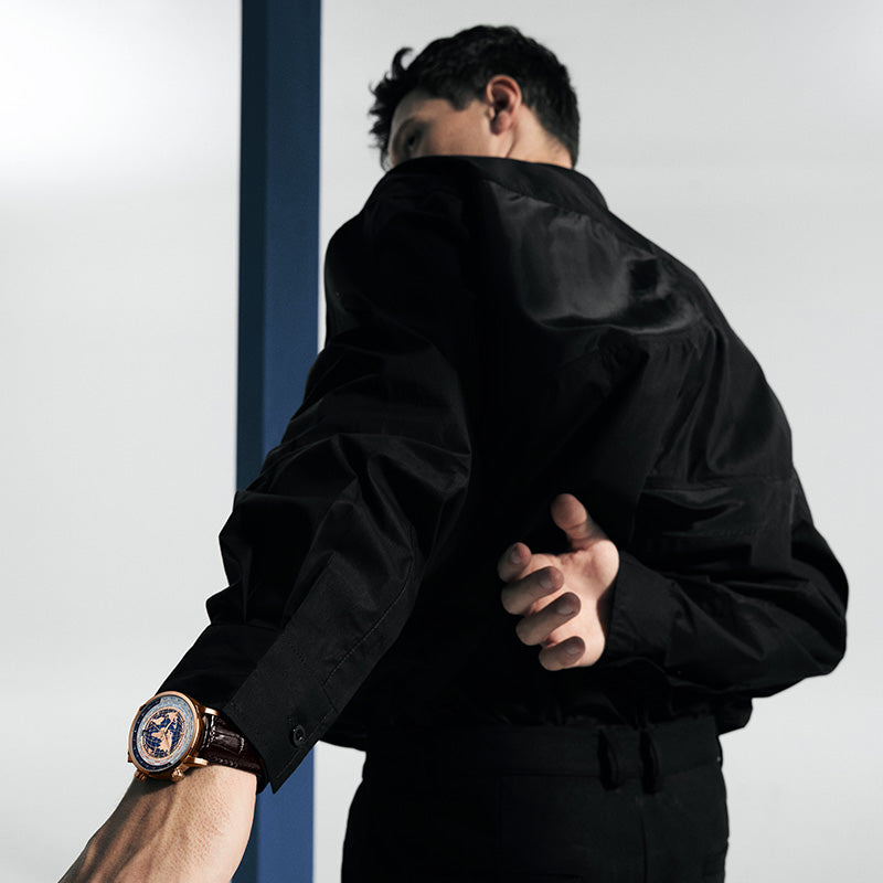 Man wearing Agelocer World Time automatic watch with blue globe dial, dynamic lifestyle shot
