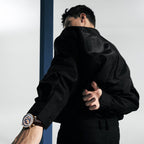 Man wearing Agelocer World Time automatic watch with blue globe dial, dynamic studio lifestyle shot