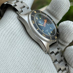 Angled view of the STEELDIVE SD1929V black dial and gilt-numeral bezel on a steel bracelet