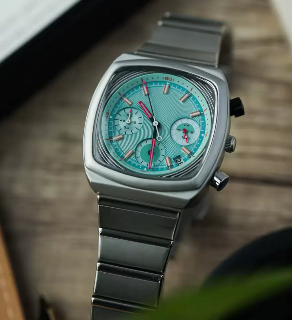 Ciloa retro chronograph watch with teal dial and stainless bracelet on wood surface