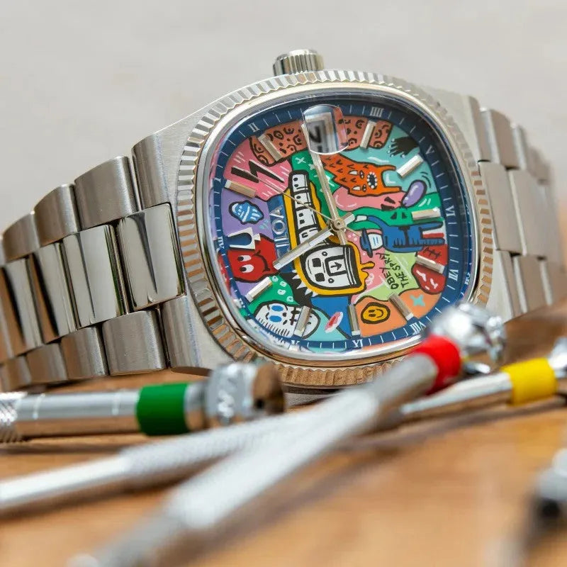 Ciloa painted dial watch with graffiti blue dial on wood surface beside watchmaker tools