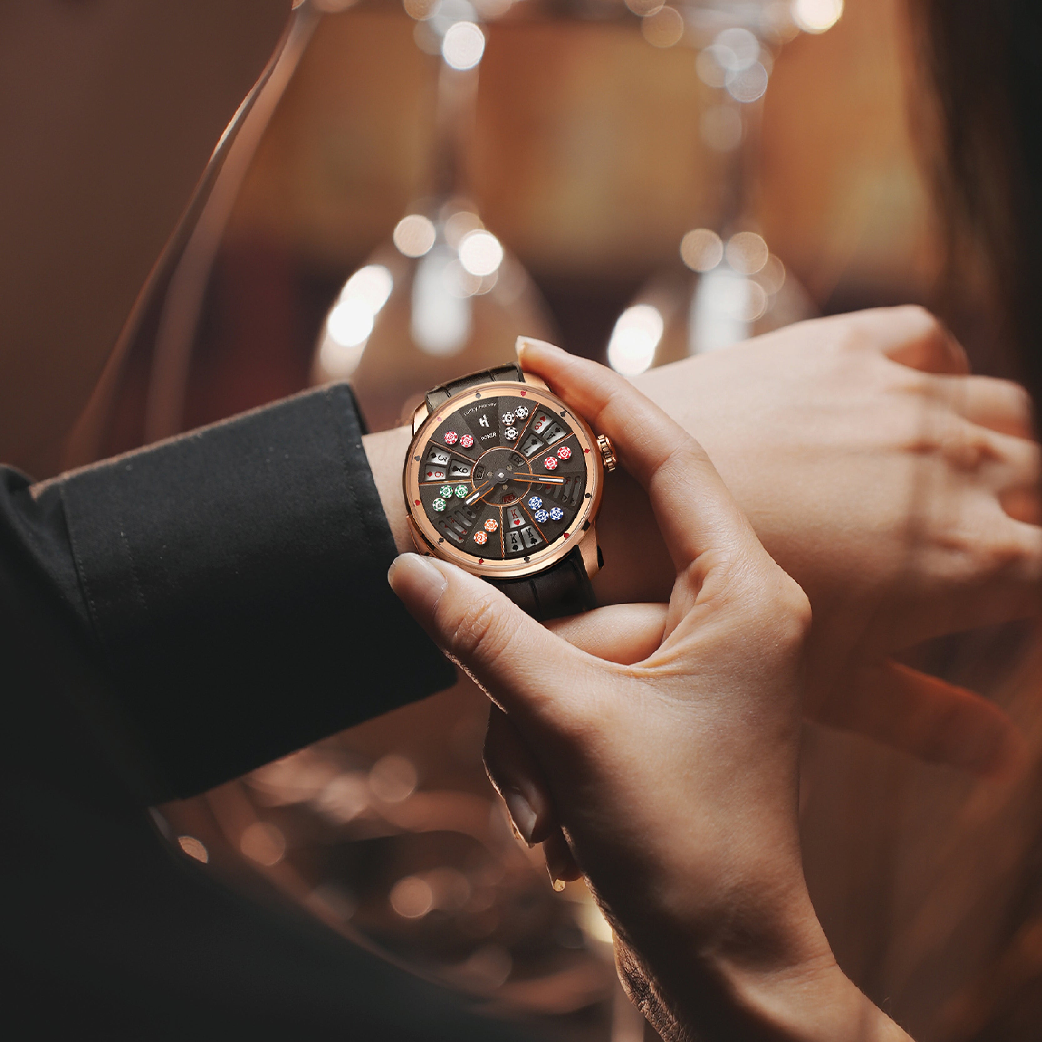 Lucky Harvey ZLS301-1 Three Card Poker rose gold watch held in hands with wine glass bokeh scene
