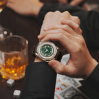 Lucky Harvey ZLS302-2 silver case green dial poker roulette watch worn on a wrist with whiskey glass and cards