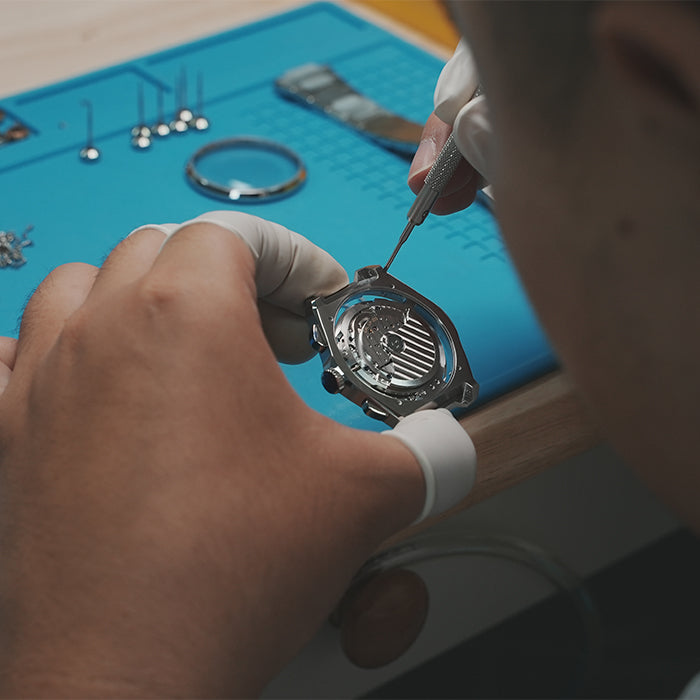 Lucky Harvey ZLS402-2 chiming watch movement being screwed into case at workbench
