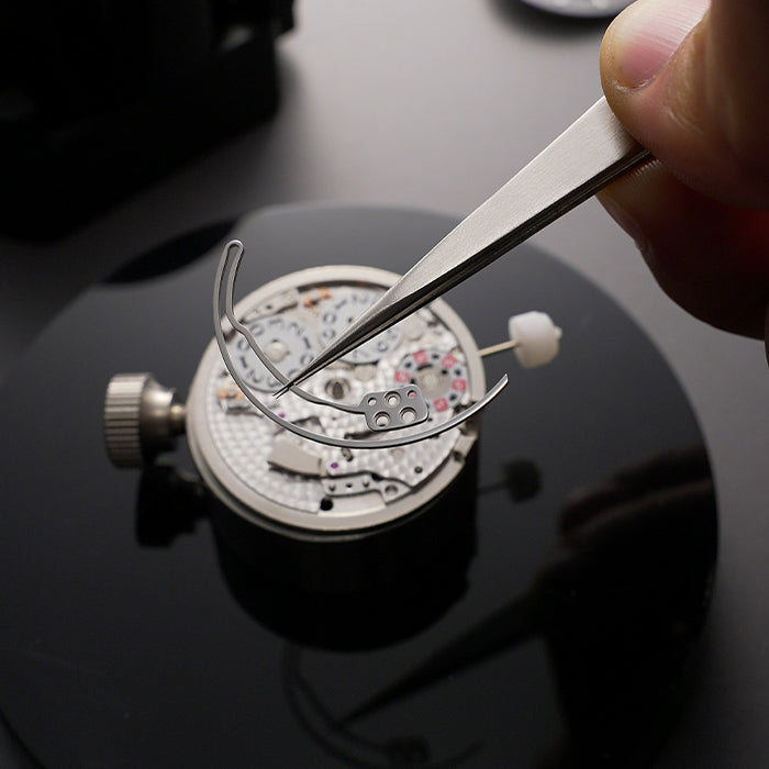 Lucky Harvey ZLS402-2 chiming watch movement with hairspring and tweezers being placed