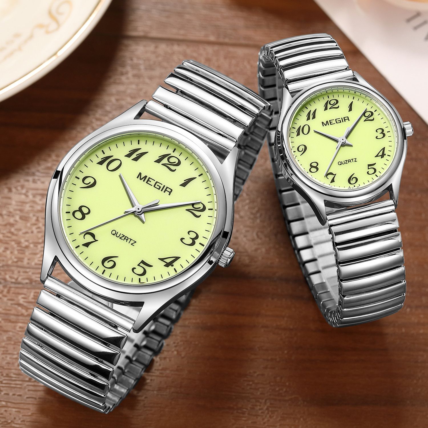 MEGIR 1088 unisex watch pair in silver-tone with luminous green Arabic-numeral dials and stretch bracelets