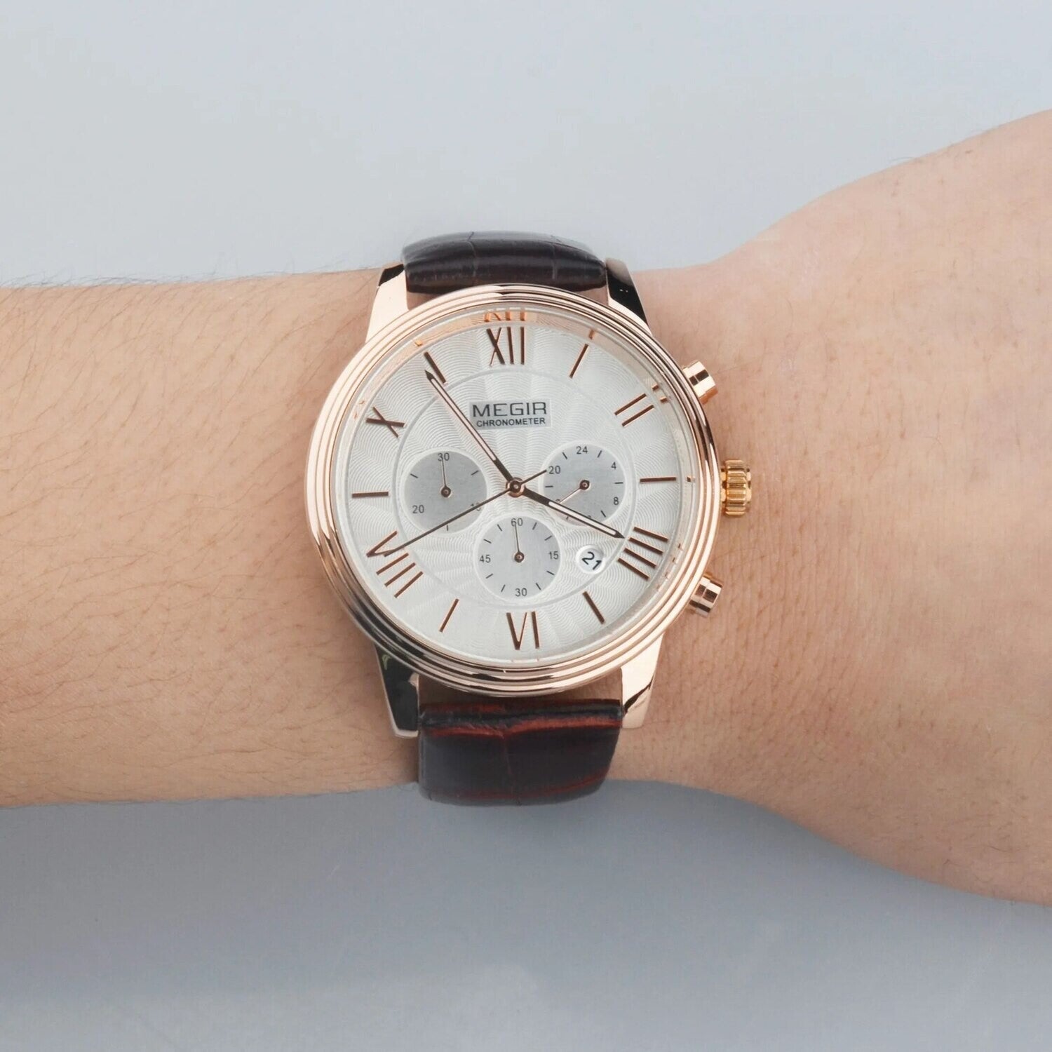 MEGIR 2012 men's chronograph watch on the wrist, rose-gold case with white dial and brown leather strap