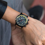 MEGIR 2110 men's chronograph watch on the wrist, black case with black dial and brown leather strap, close-up