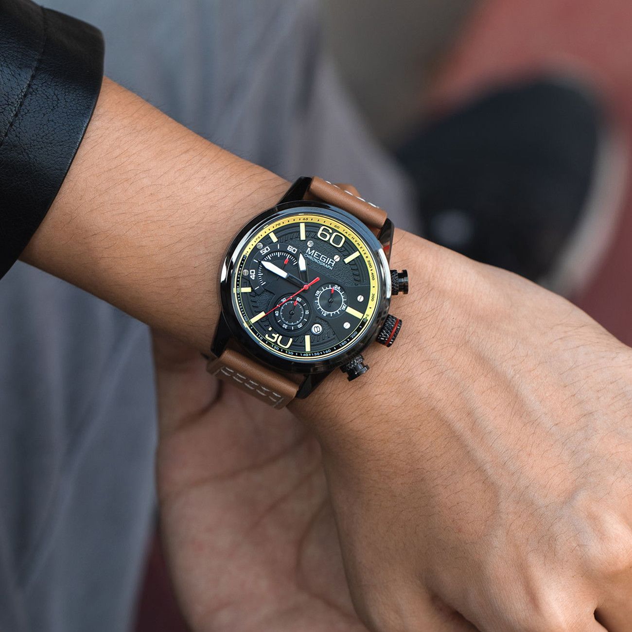 MEGIR 2110 men's chronograph watch on the wrist, black case with black dial and brown leather strap, close-up
