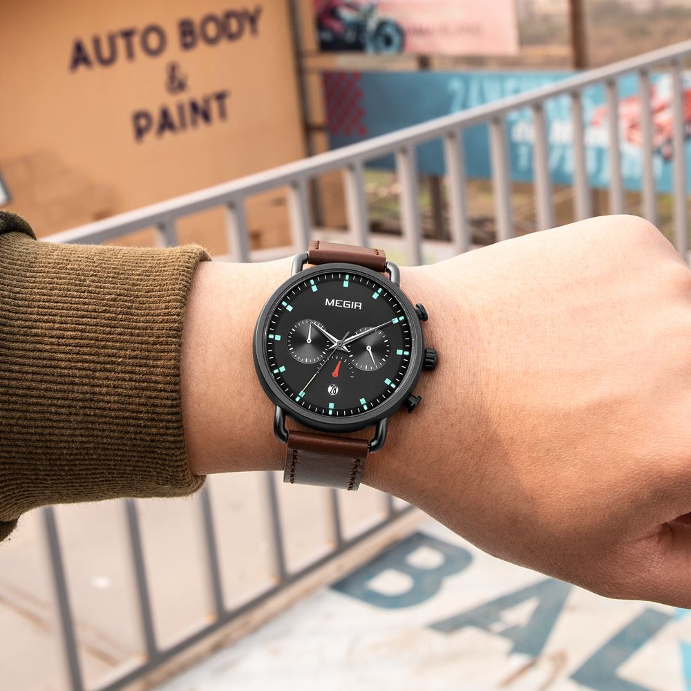 MEGIR 2159 men's chronograph watch on the wrist, black case with black dial and brown leather strap, close-up