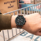 MEGIR 2159 men's chronograph watch on the wrist, black case with black dial and brown leather strap, close-up