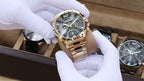 MEGIR 2221 men's chronograph watch held in gloved hands, gold-tone case with gray-black skeleton dial and gold bracelet