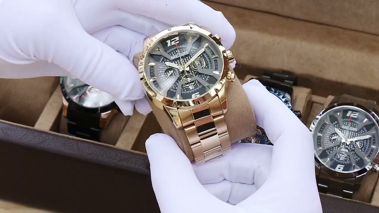 MEGIR 2221 men's chronograph watch held in gloved hands, gold-tone case with gray-black skeleton dial and gold bracelet