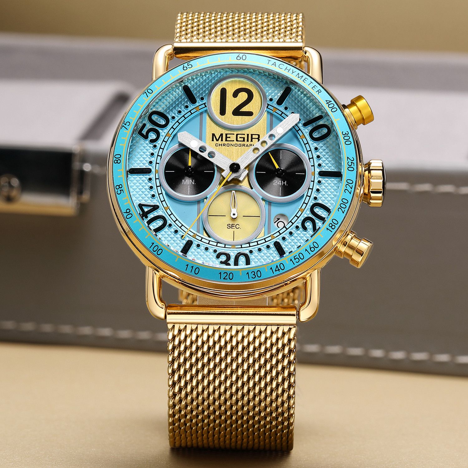 MEGIR 2249 men's chronograph watch, gold-tone case with light blue dial, tachymeter bezel and gold mesh bracelet, angled view