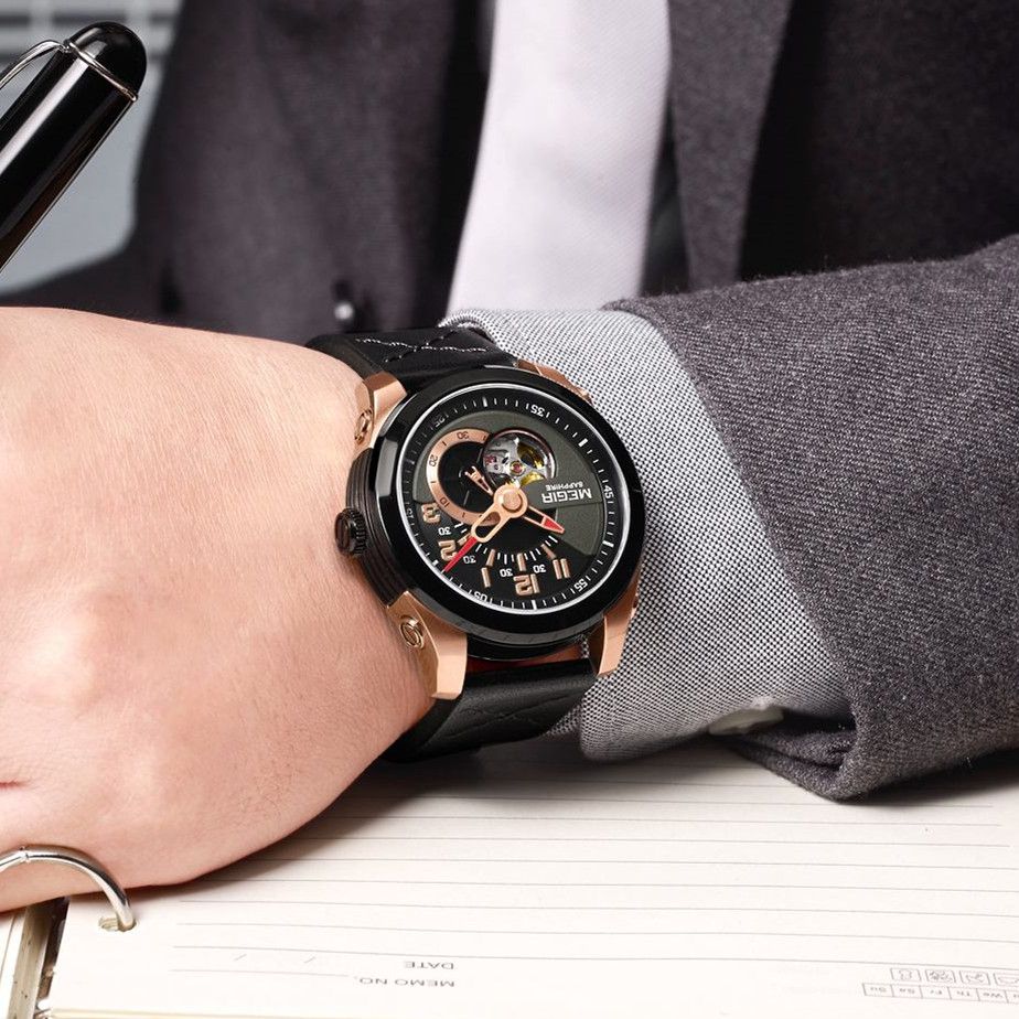 MEGIR 62050 automatic watch on the wrist, rose-gold and black case, black open-heart dial and black leather strap, at a desk