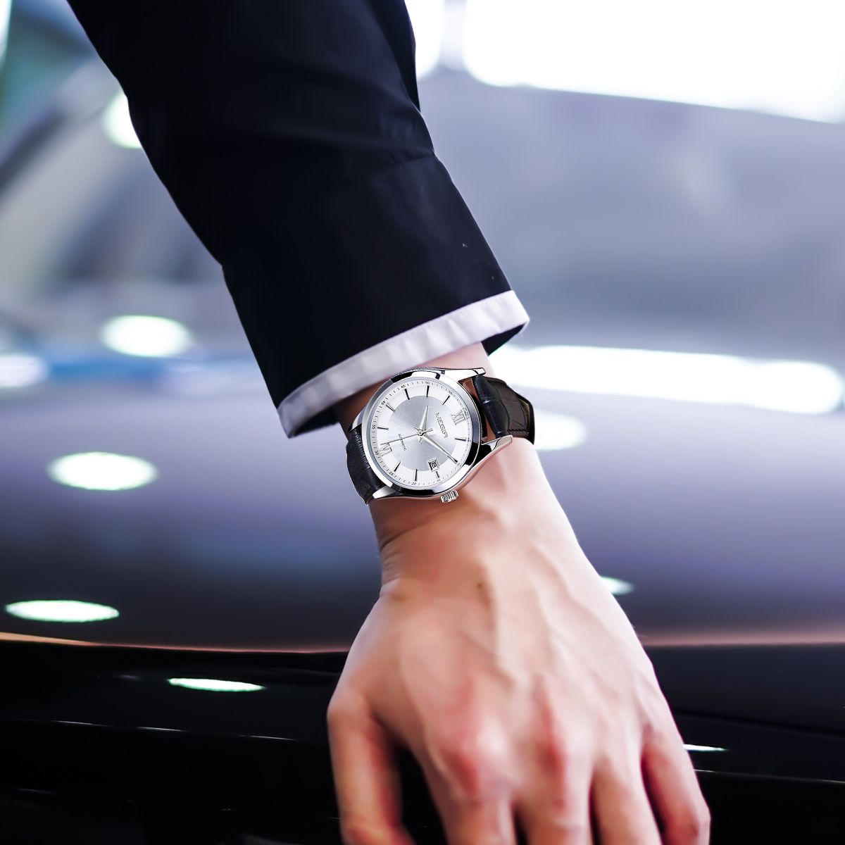 MEGIR 62063 automatic watch on the wrist, silver case, silver-white dial and black leather strap, in an underpass