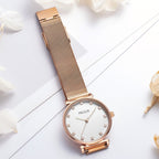 MEGIR 7001 women's quartz watch, rose-gold mesh bracelet and white crystal-marker dial, flat-lay with dried flowers