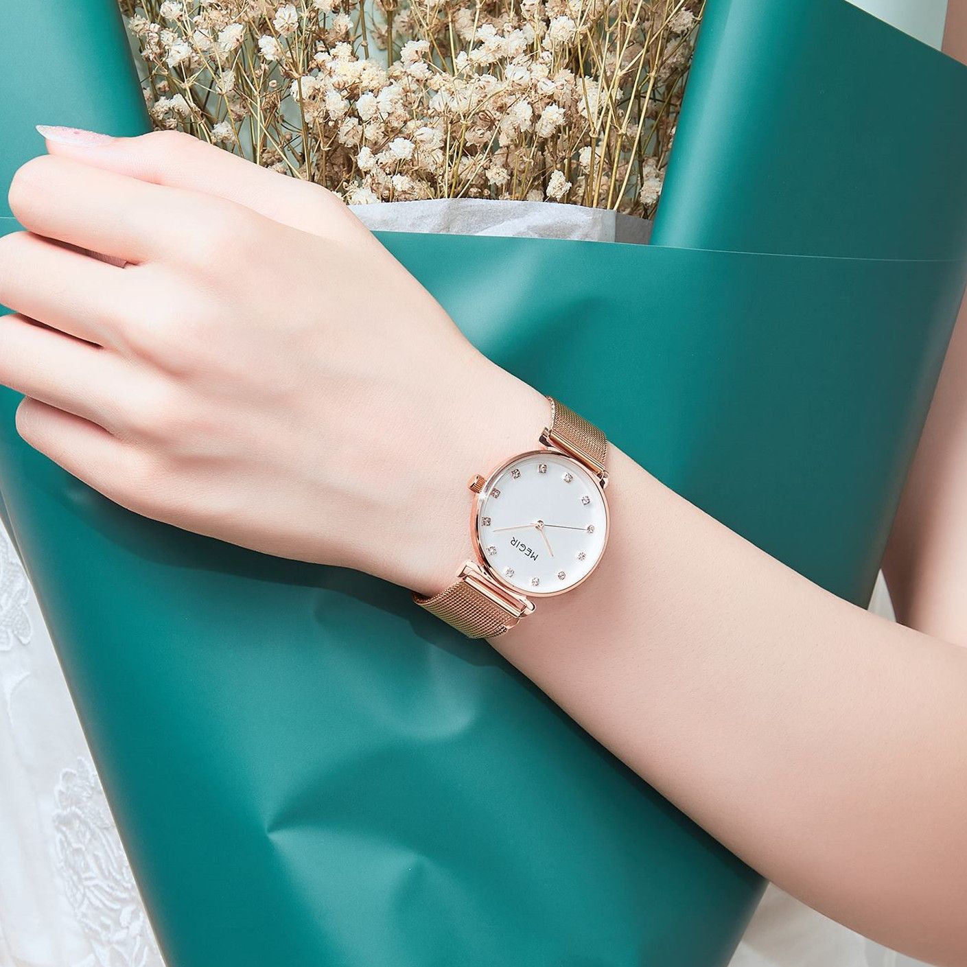 MEGIR 7001 quartz watch on the wrist, rose-gold mesh bracelet and white crystal-marker dial, teal background